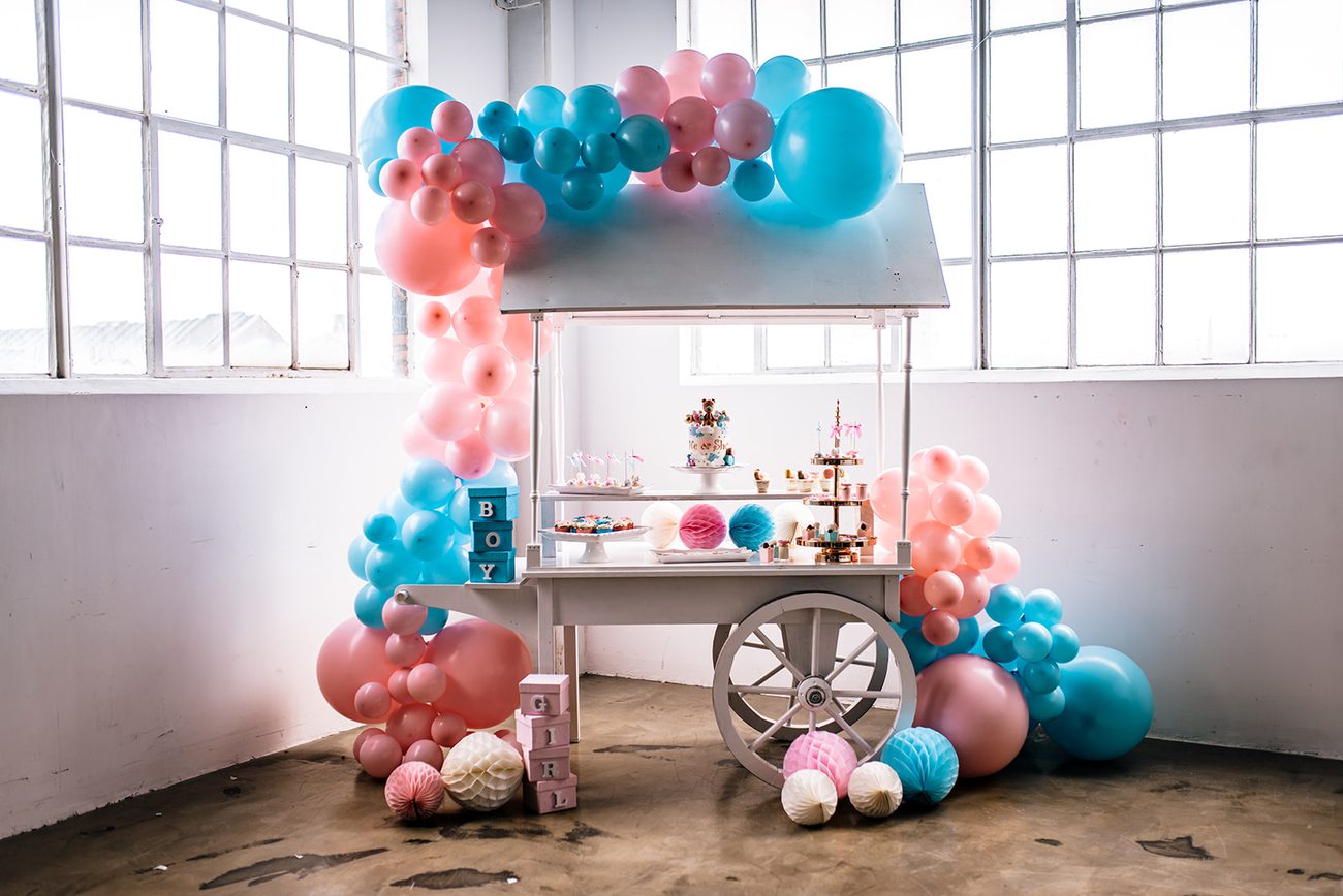Weißer Candywagen mit pastellfarbenem Ballonbogen, Torte und Süßigkeiten
