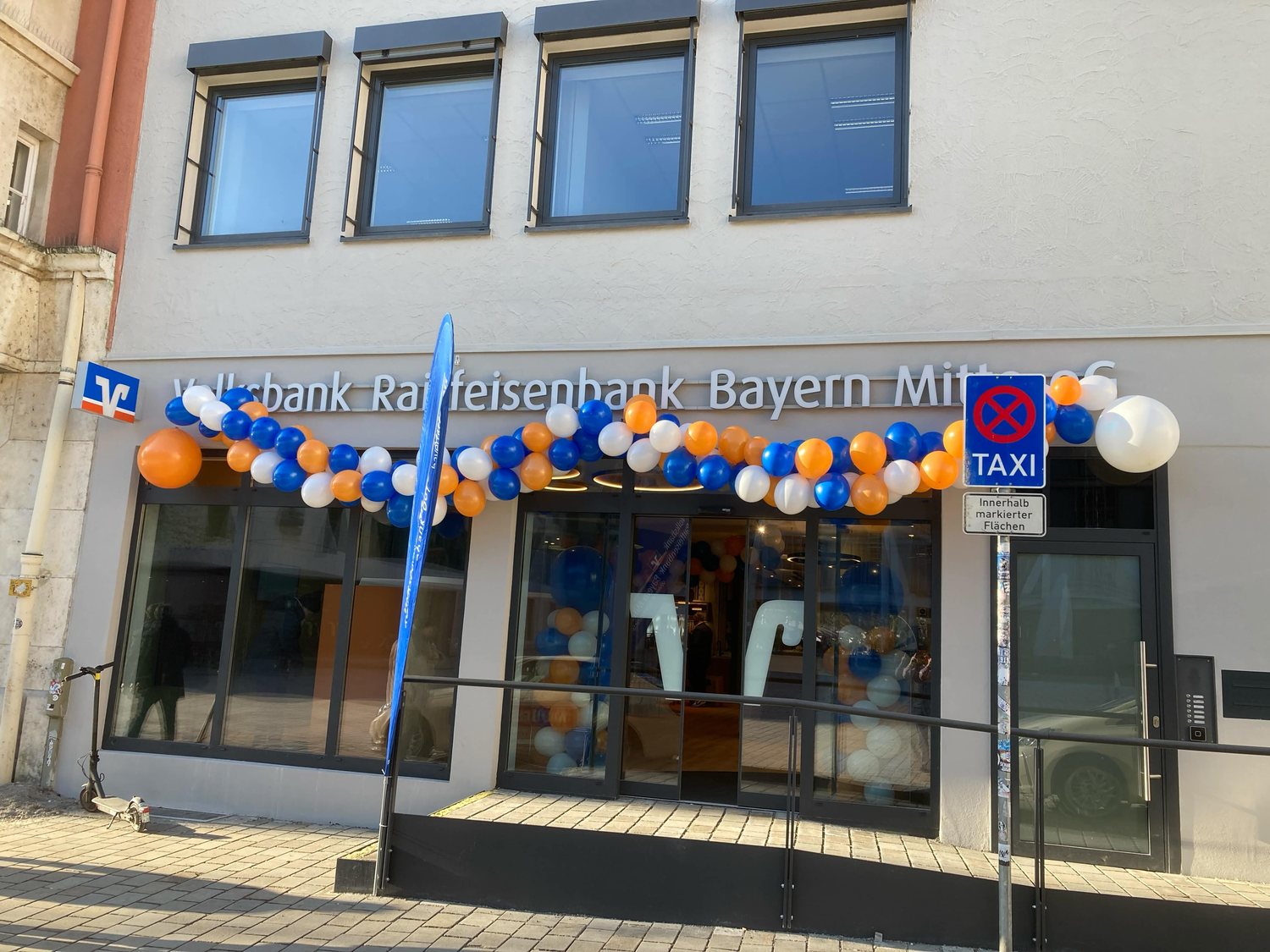 Ballongirlande in Markenfarben über dem Eingang der Volksbank Raiffeisenbank Bayern Mitte